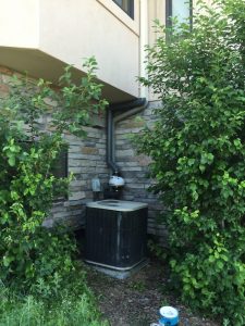 image of a radon mitigation system installed on a home near an AC unit
